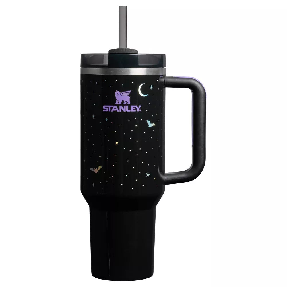 Limited edition Stanley Quencher H2.0 40 oz tumbler in a black night sky print, featuring white and iridescent stars, a crescent moon, and bats. The tumbler has a black handle with a purple comfort grip and a dark gray straw.