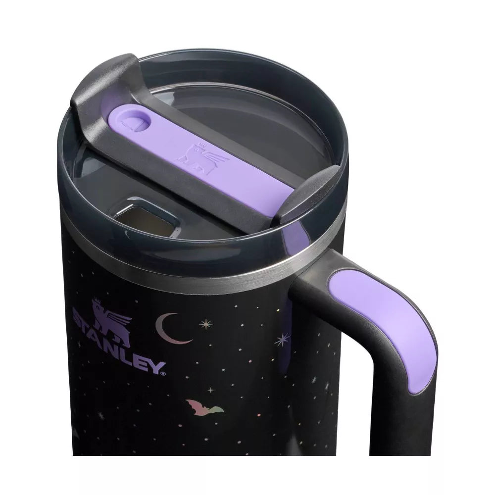 Front view of the Stanley 40 oz tumbler in a Gothic/Spooky Night Sky black print. The design includes a crescent moon, bats, and stars, with the iridescent Stanley logo prominent. Features include a black handle and a dark gray straw.